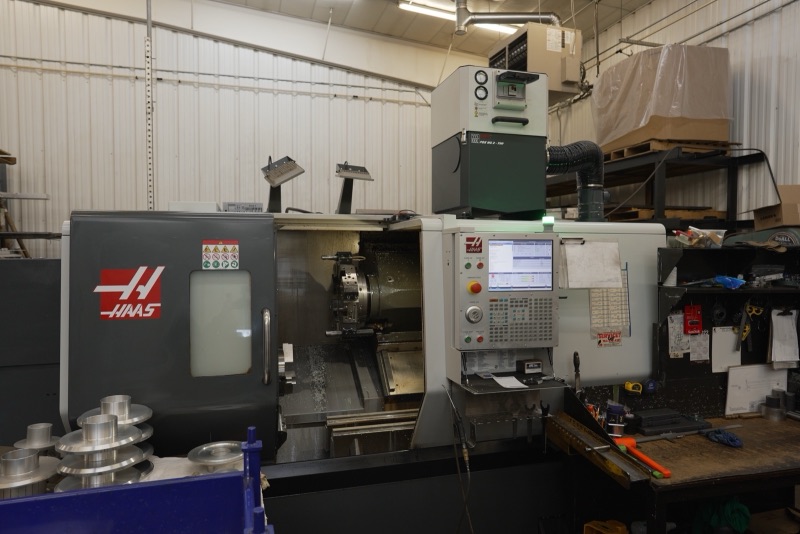 Haas CNC turning center with finished aluminum parts in the foreground