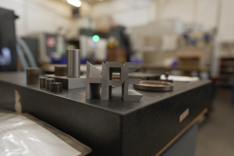 Machined steel HPE letters on a granite inspection table in the shop