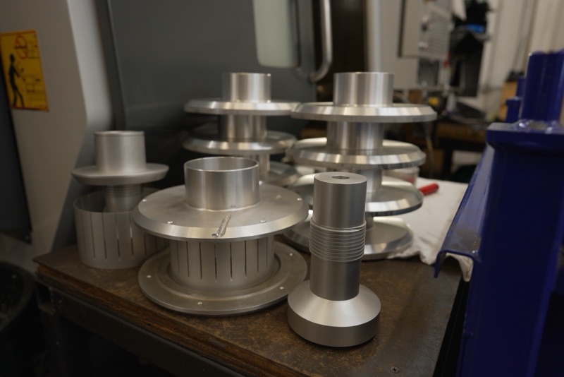 Stacked precision-machined aluminum spools on a shop cart